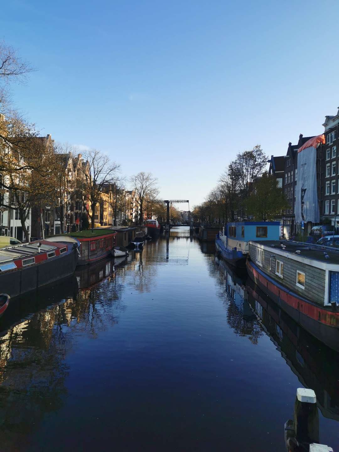 Amsterdam canal with houseboats under a blue sky