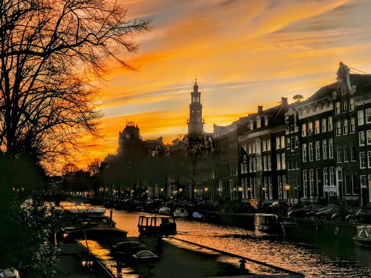 Amsterdam canal at golden hour sunset with the Westerkerk tower