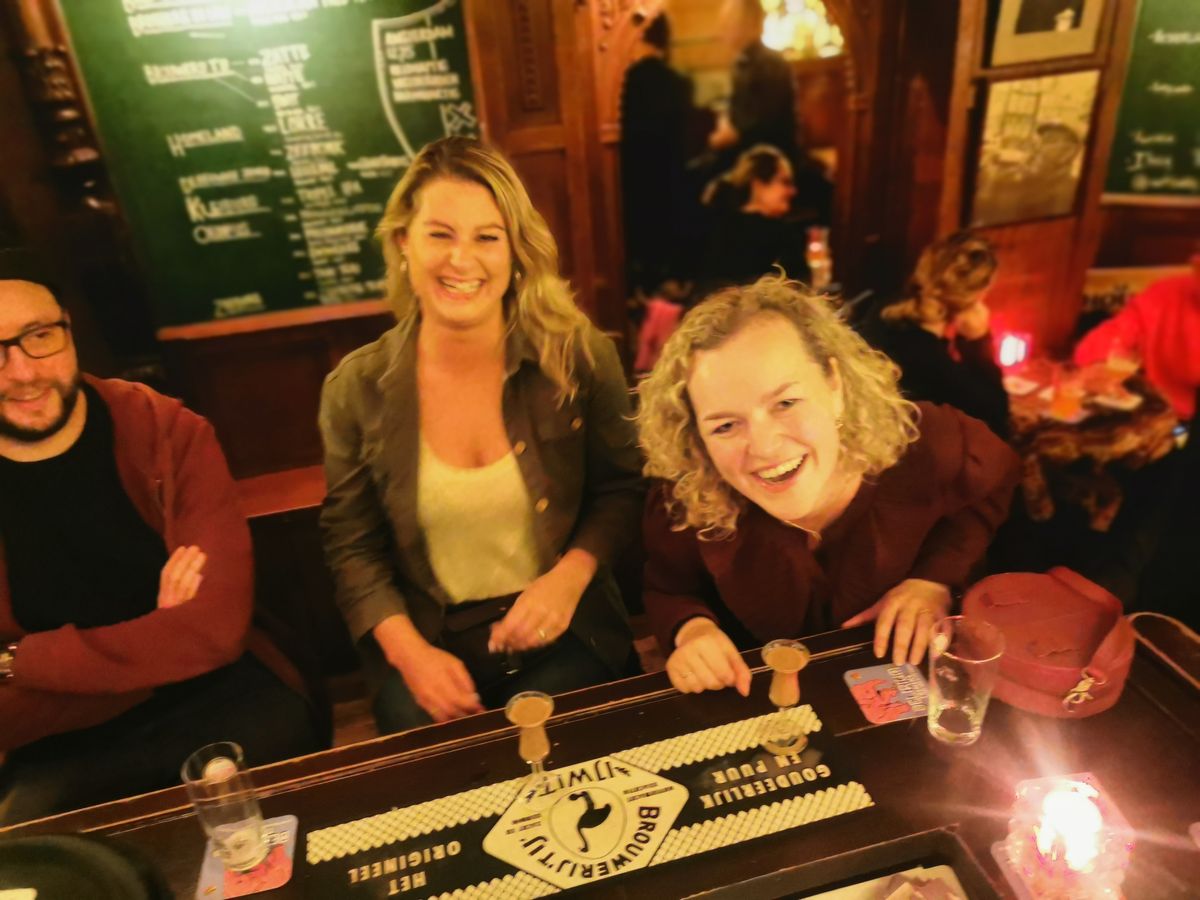 Guests laughing at the bar of a traditional Amsterdam brown cafe