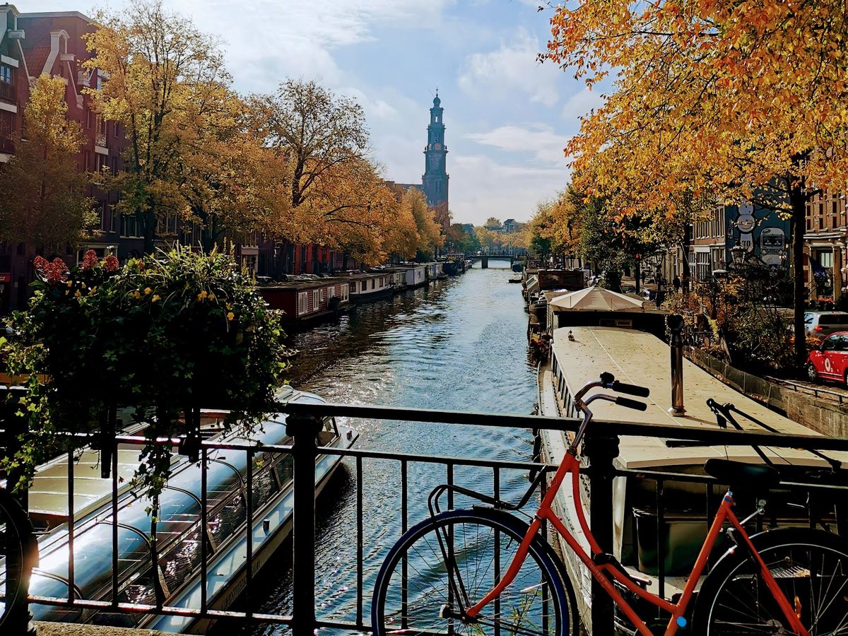 Orange bike on a bridge over the Prinsengracht with the Westerkerk tower