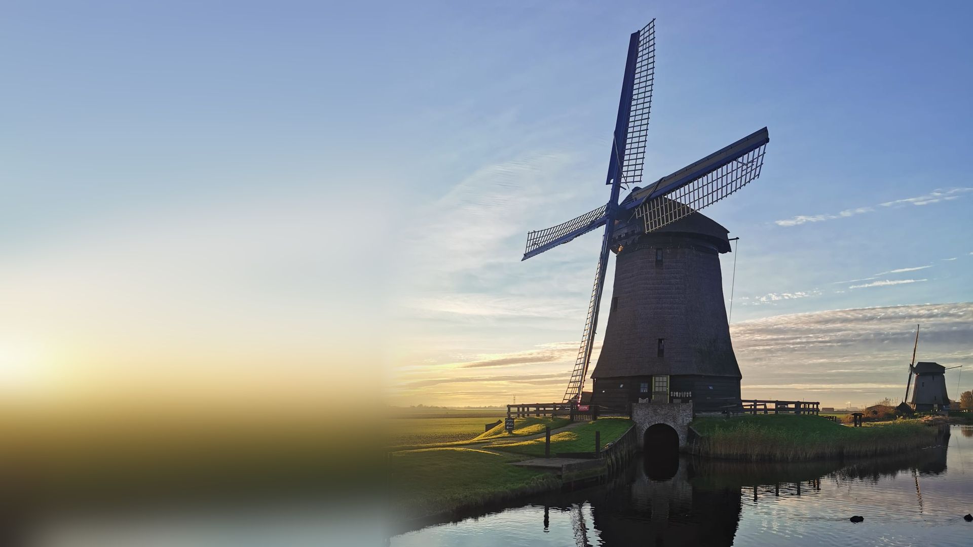 Traditional Dutch windmill at sunrise, reflected in a polder canal